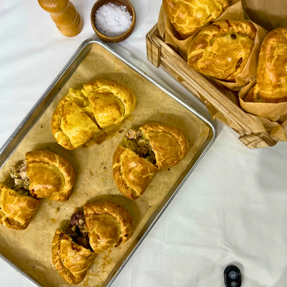 Baked Ansum pasties cut open on a tray showing mixed fillings